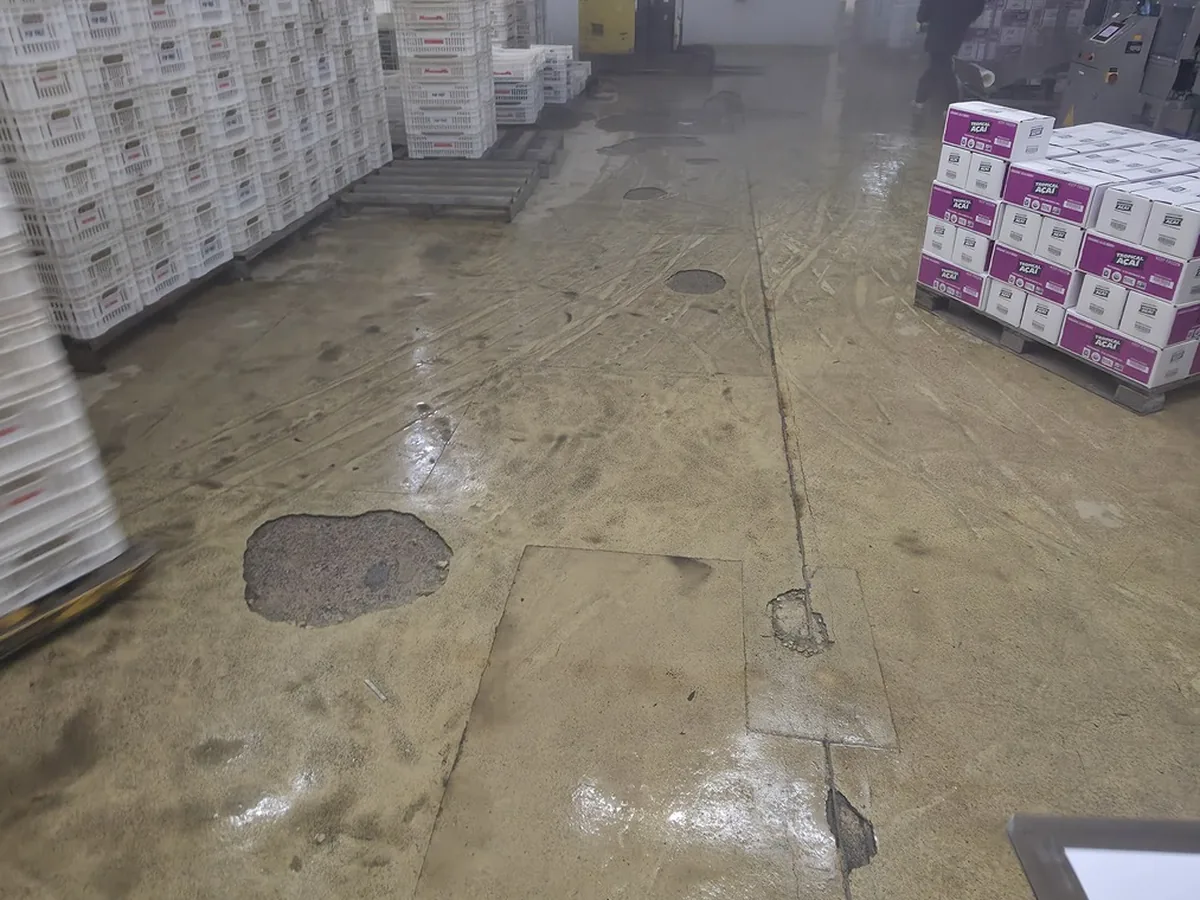 Piso de concreto exposto e desgastado de um salão de produção antes da obra